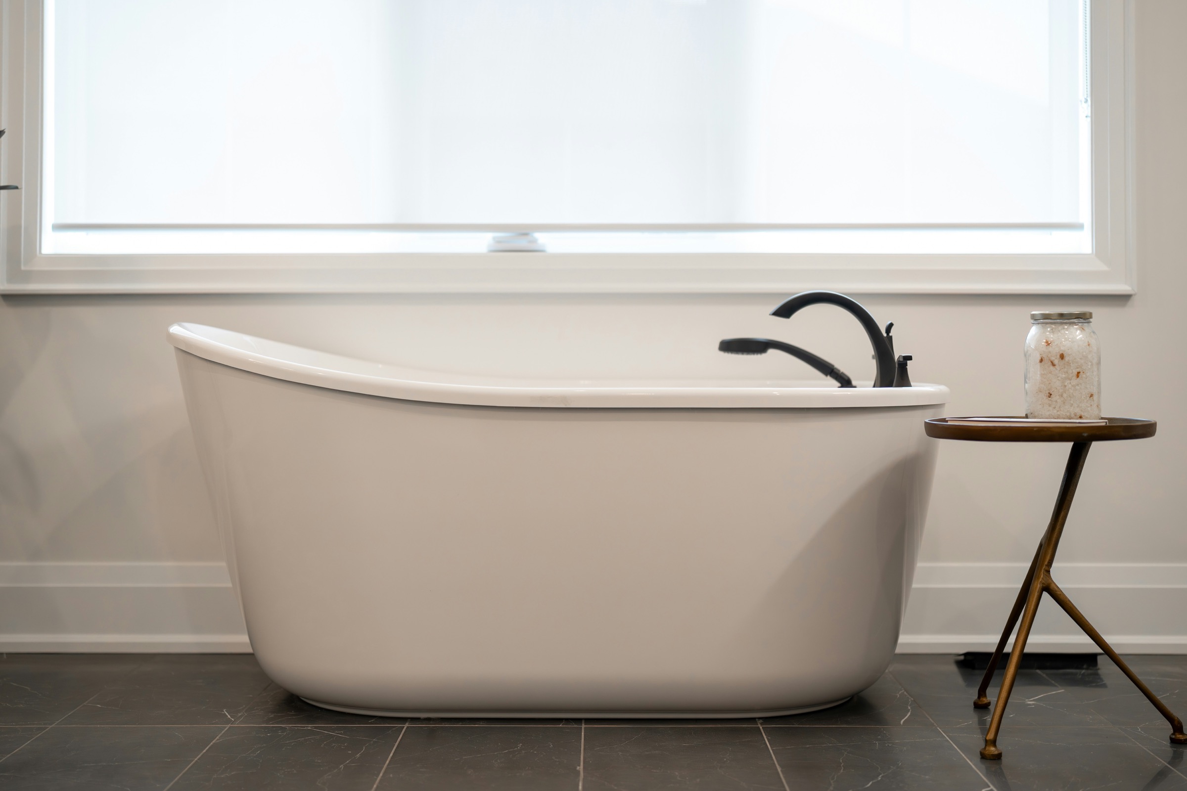 Freestanding bathtub with black faucet and side table